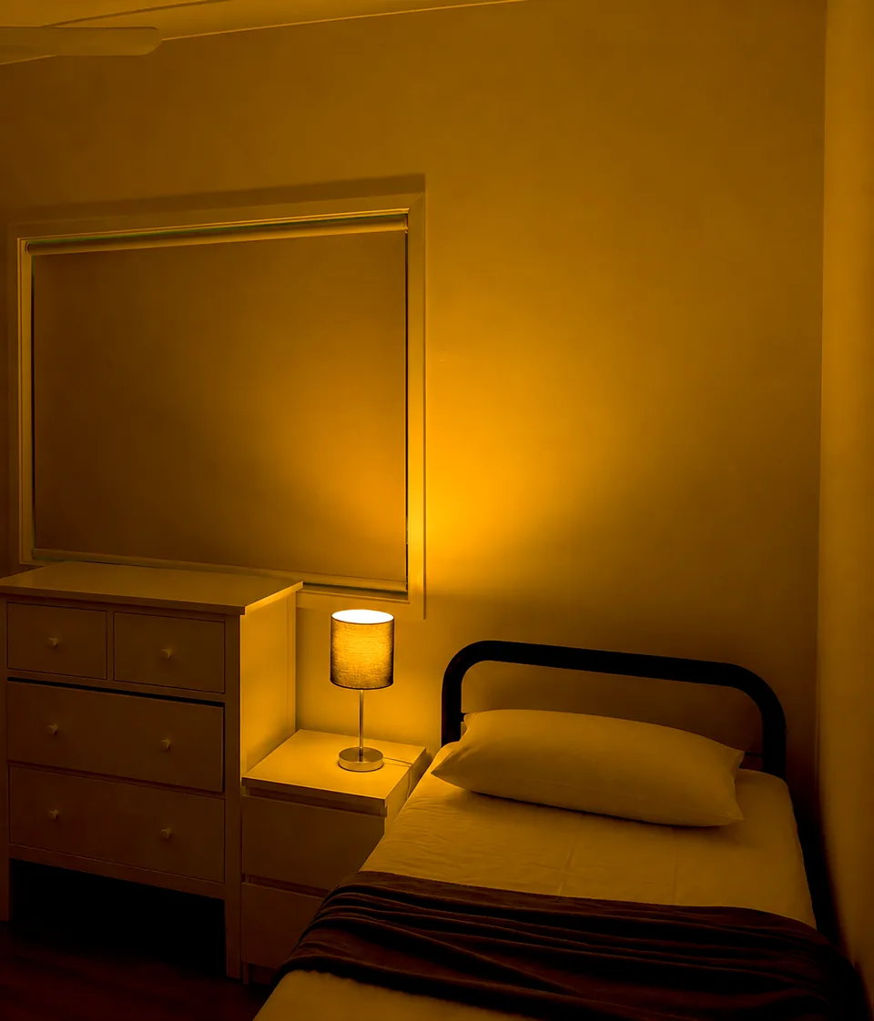 The same shelter bedroom with warm amber bedside lighting