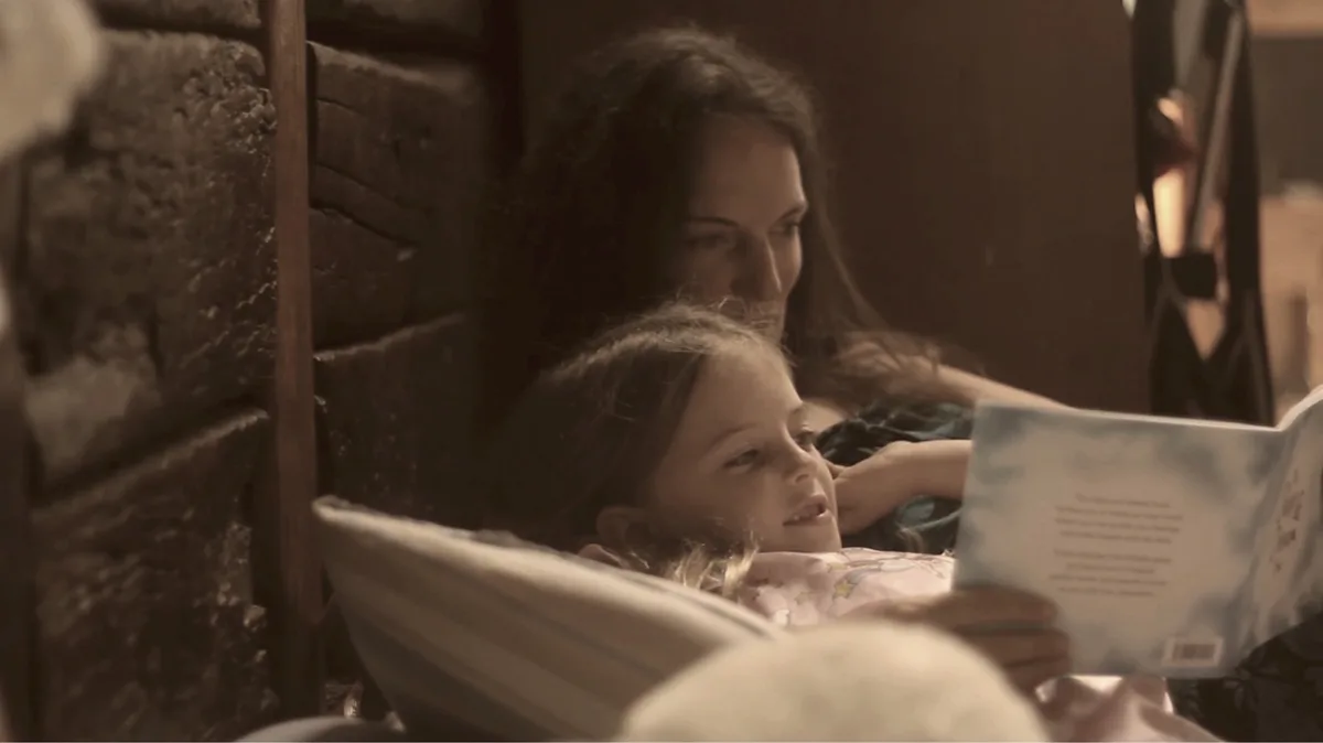 A mother and child sharing The Sleep & Dream Book together in bed