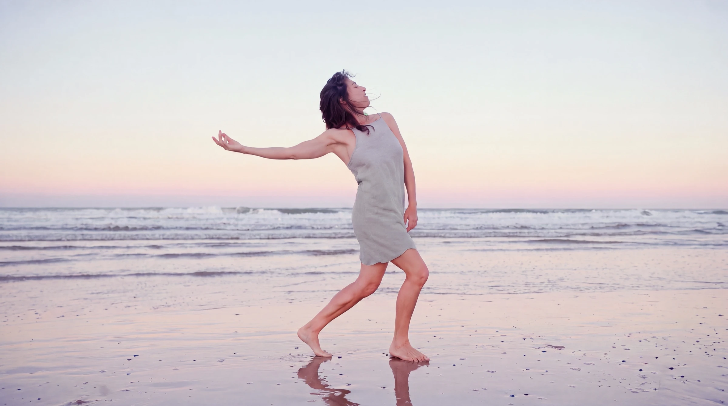 Ahna dancing freely at the ocean’s edge at dusk