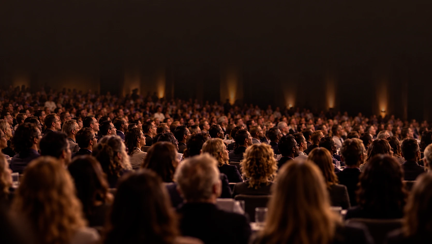 An audience listening in a warmly lit auditorium